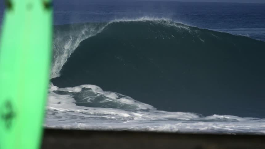 Large wave crashes against the beach shoreline
