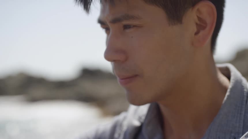 A man sits on the beach with a musical instrument