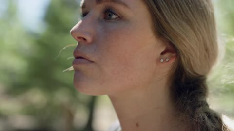 Freckled blonde woman looks up in the forest