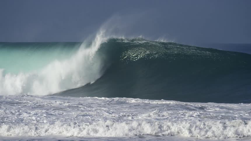 A large wave crashes towards the shore