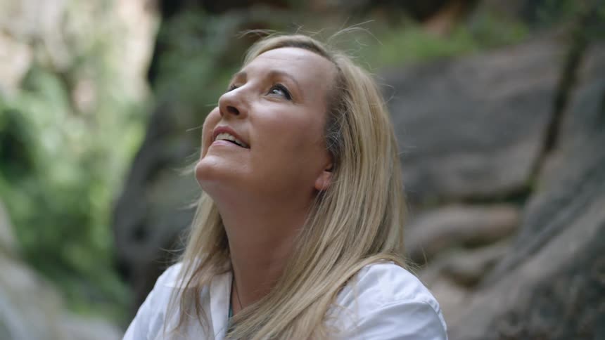 A woman looks up at a mountain