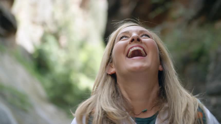A woman raises her arms yelling as she smiles