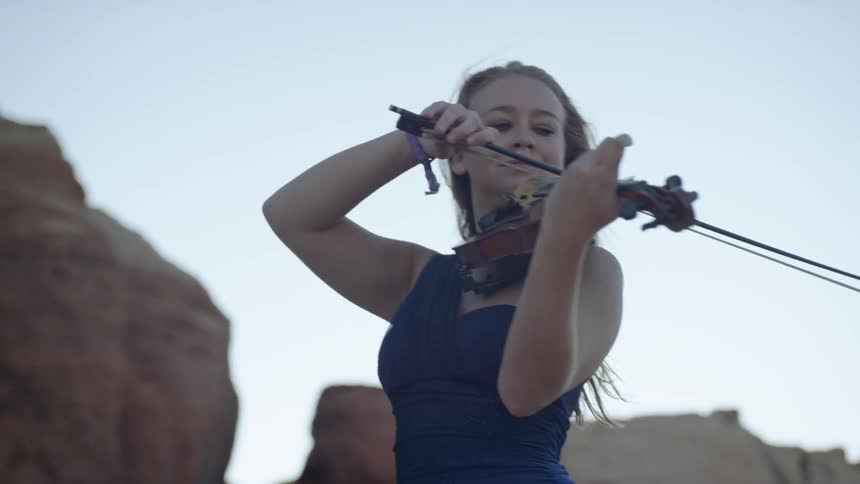 A woman is playing the violin outside