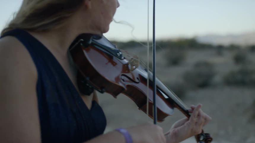 A young woman plays the violin outside