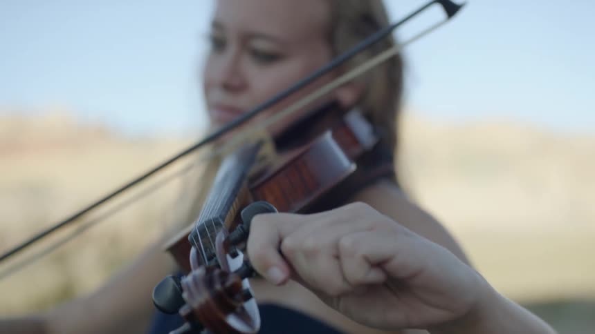 A woman is playing a musical instrument outdoors
