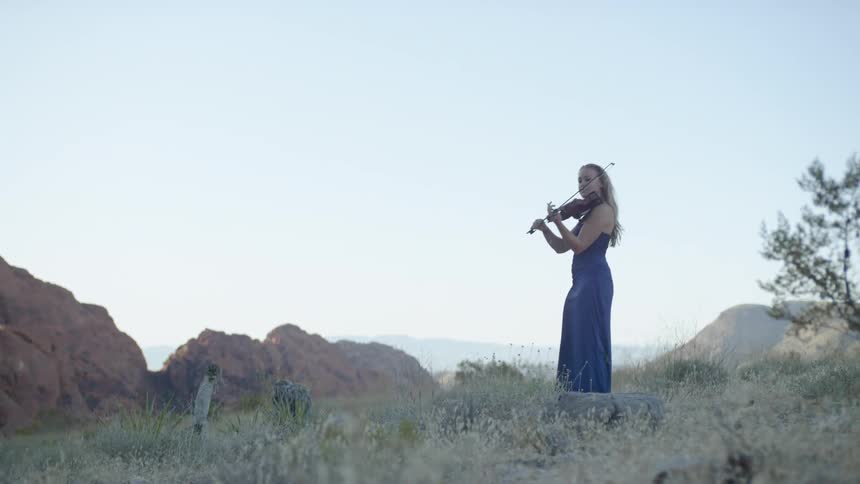 A young girl plays a musical instrument outside