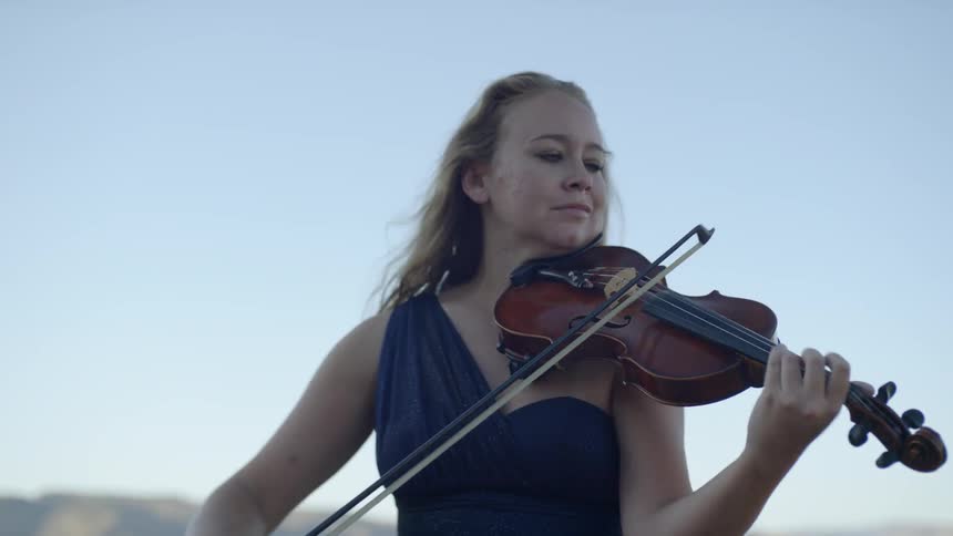 A woman is playing the violin on a sunny day