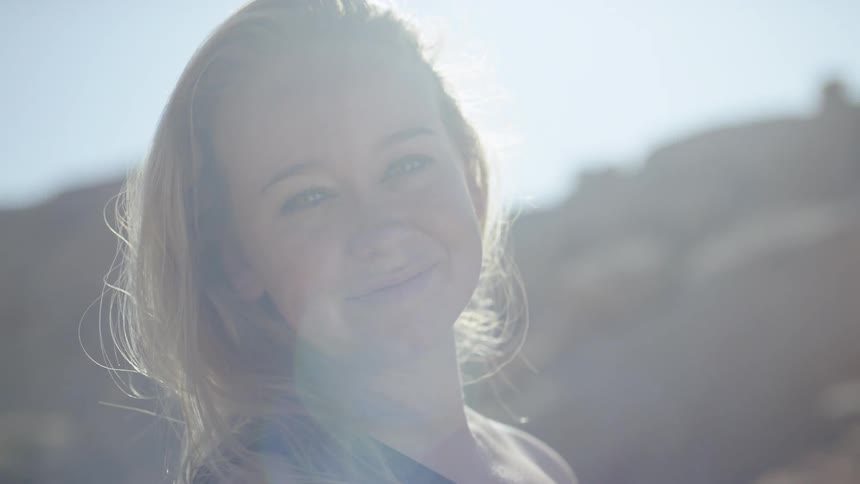 An older blonde woman smiles while standing outdoors