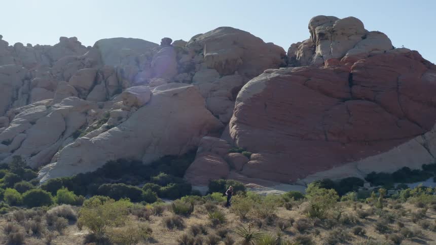 Aerial of a female in a formal dress playing a violin in the canyon