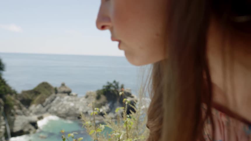 A woman draws on a piece of paper next to the beach