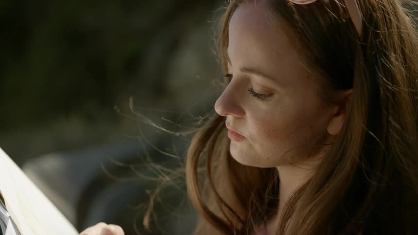 A young woman sketches while sitting outdoors