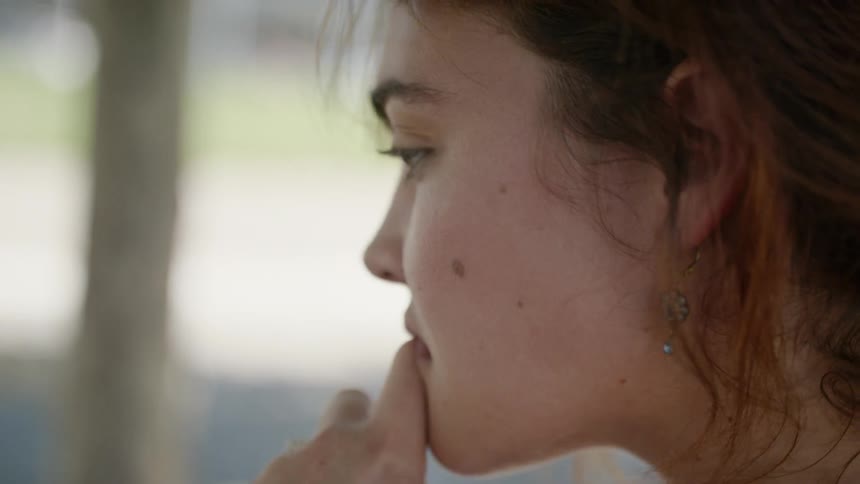 A woman touches her face looking at something