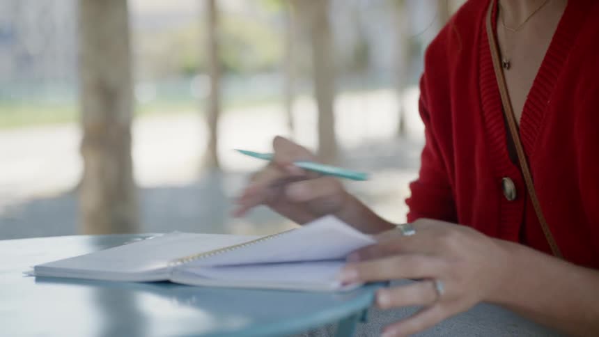 A young girl sits outside and flips through a notebook