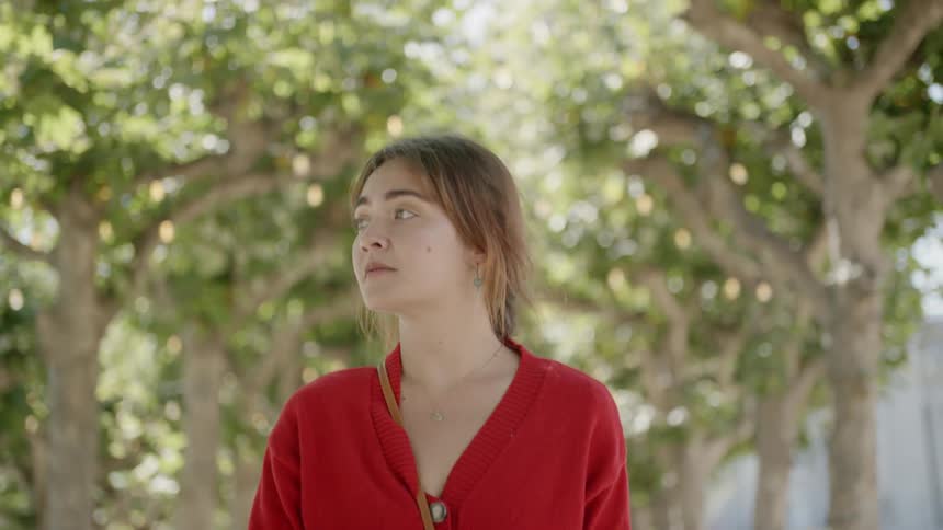A young girl walks through a treed path and looks around