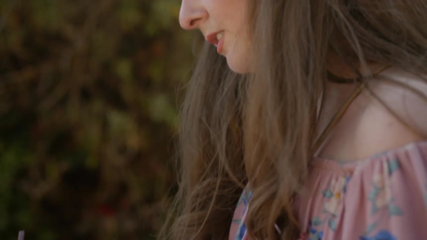A woman is writing in a notebook outdoors