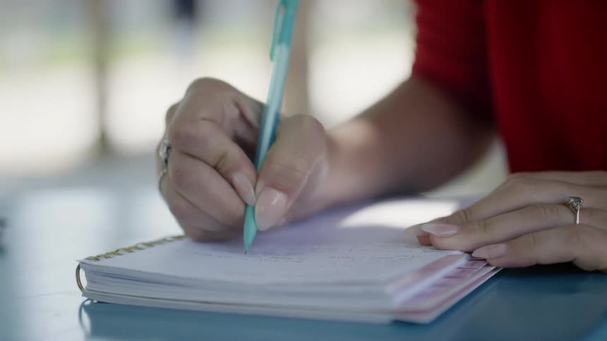 A white woman writes in a notebook