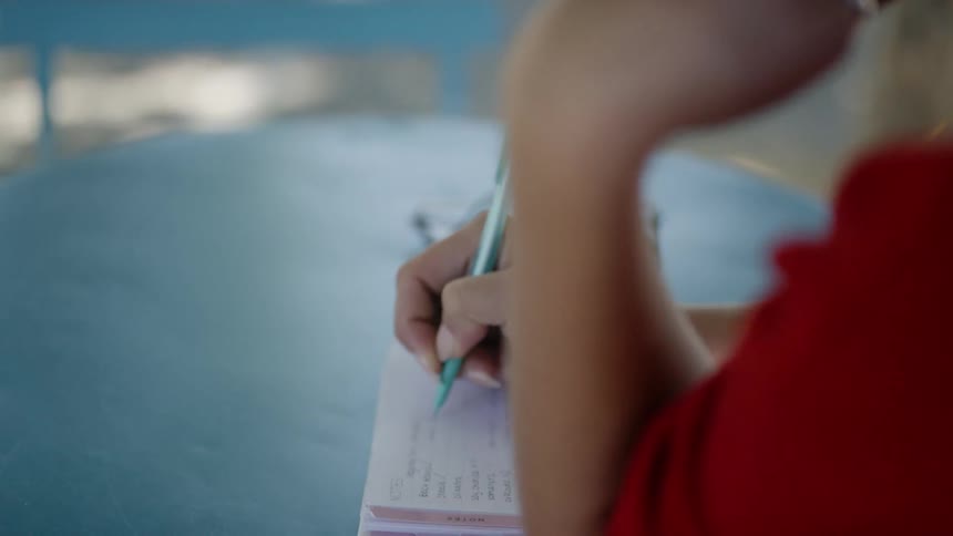 A person is writing in a notebook