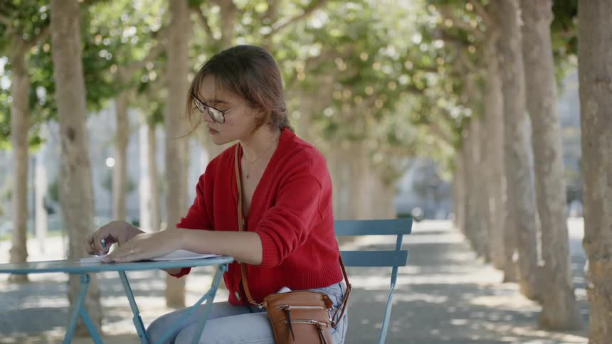 A young girl sits at a table and flips through a book