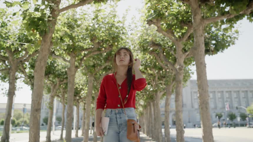 Woman walking on path surrounded by small trees on city park