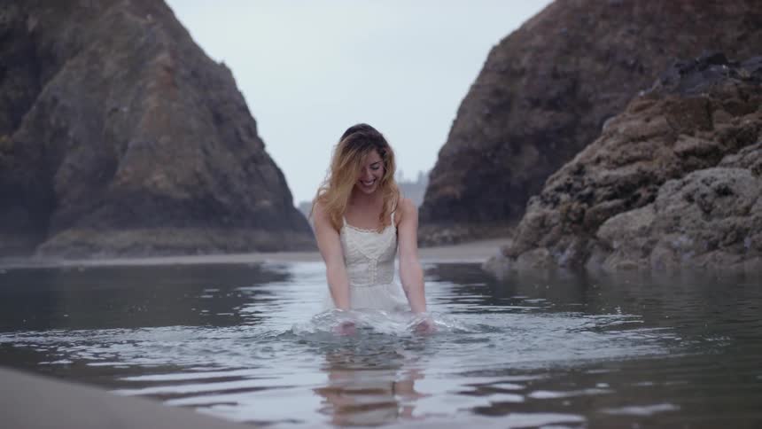 A woman in a white dress playing in shallow water