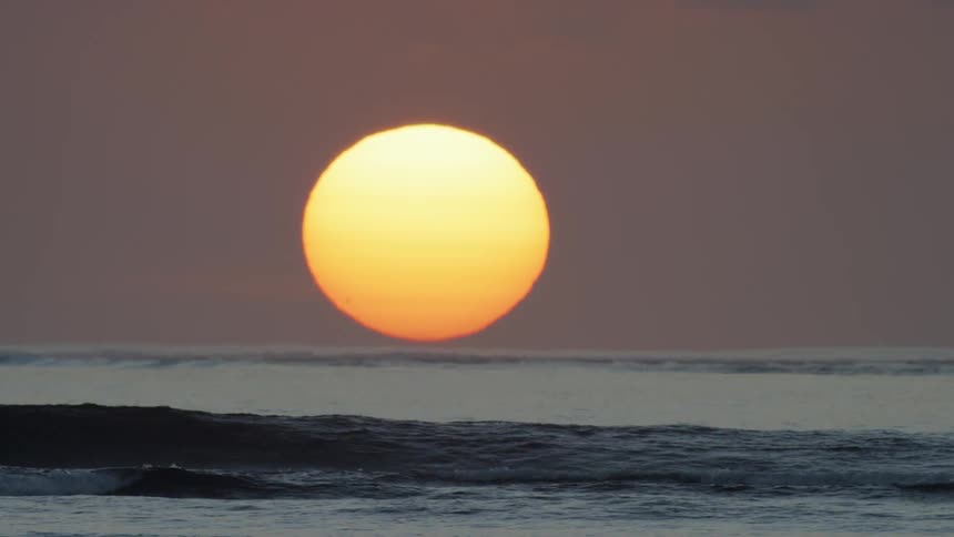 Waves landing on a beach at sunset