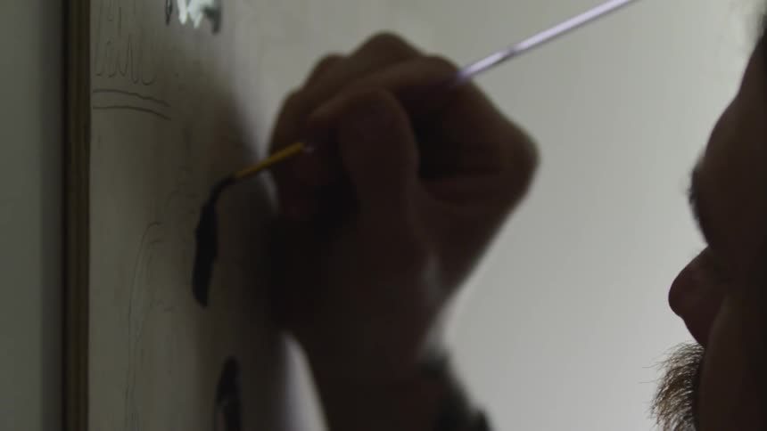 An artist paints on a canvas