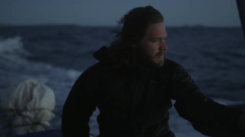 A man is steering a boat at sunset