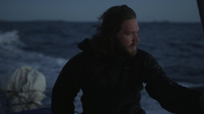 A man is steering a boat at sunset
