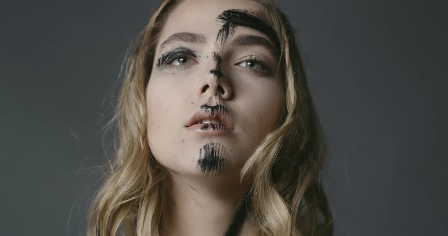 A model has black paint smeared on her forehead nose and chin