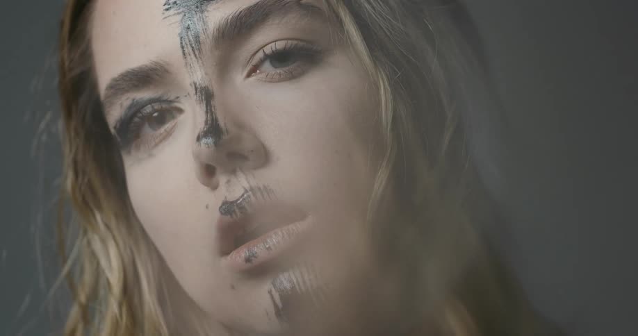 Young woman with a smudge of black paint on her face poses for a camera