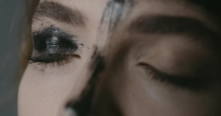 A woman has black makeup smeared on her nose and one eye