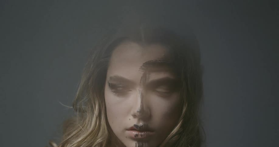 A model poses with black paint brushed down her face
