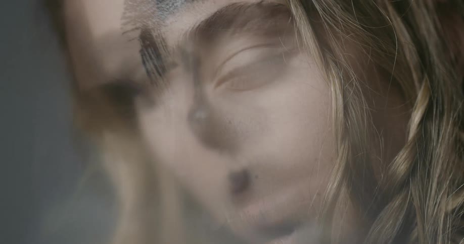 A woman with paint on her face blinks