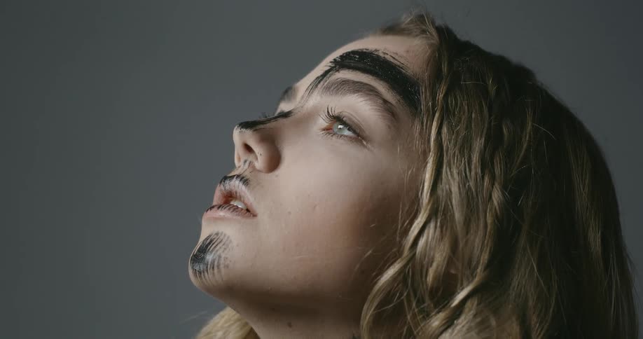 A woman posing for a photo has black paint on her face