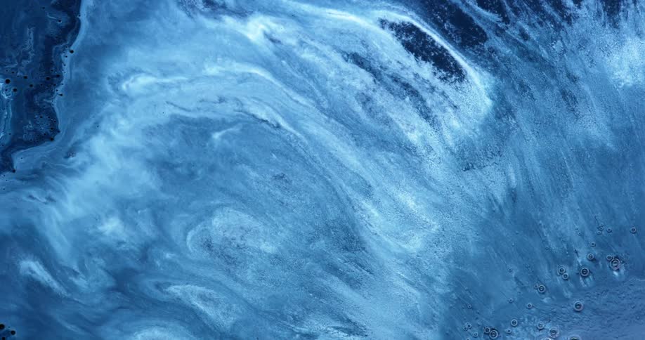 Blue paint swirls and flows over a surface