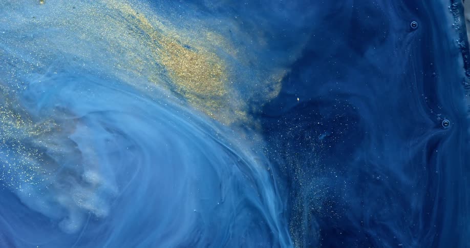 A liquid with blue hues and golden glitter particles swirls and mixes around