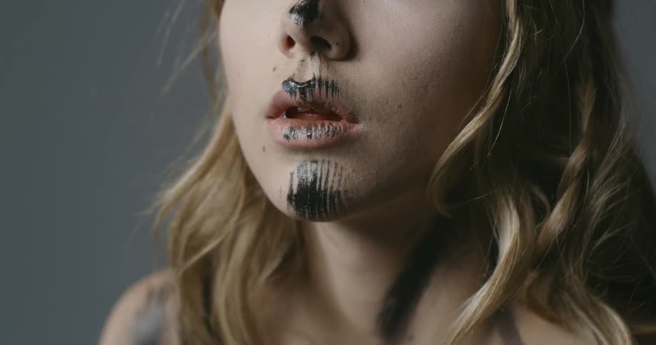 Face of a young woman covered with a smudge of black pain