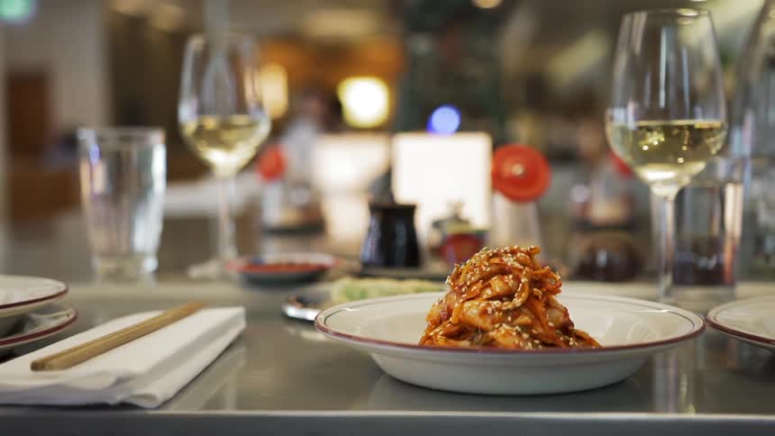 View of dinner plates, chopsticks, glasses, a bottle and wine glasses set on a table