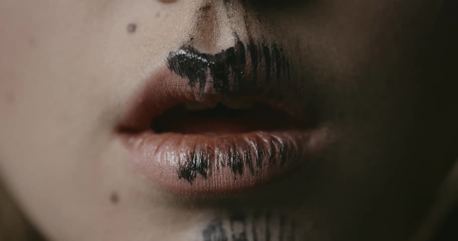 A close up of a young womans mouth with black body paint on it