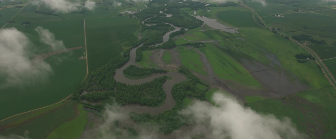 A river winds through grassy plains on a cloudy day