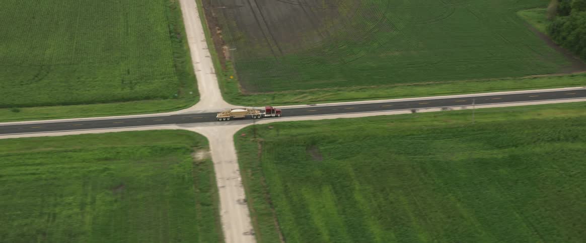 A semi truck hauls aggregate on a highway across open plains