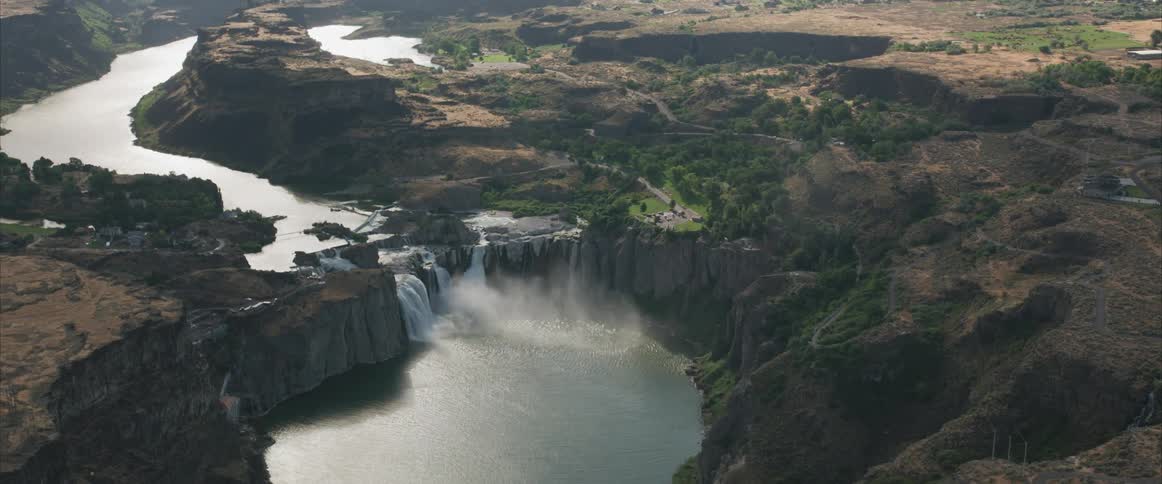 An aerial view of a river flowing over a cliff in the wilderness
