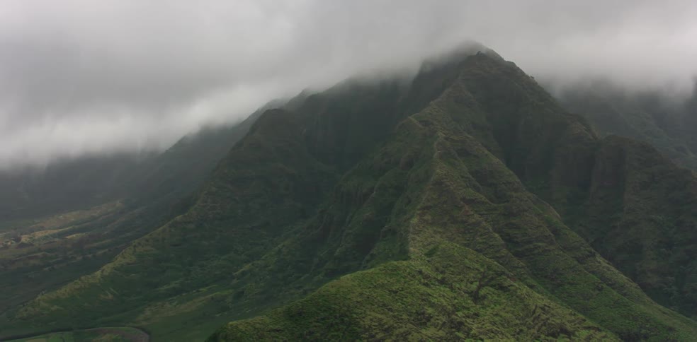 Clouds hang low over vegitated mountains