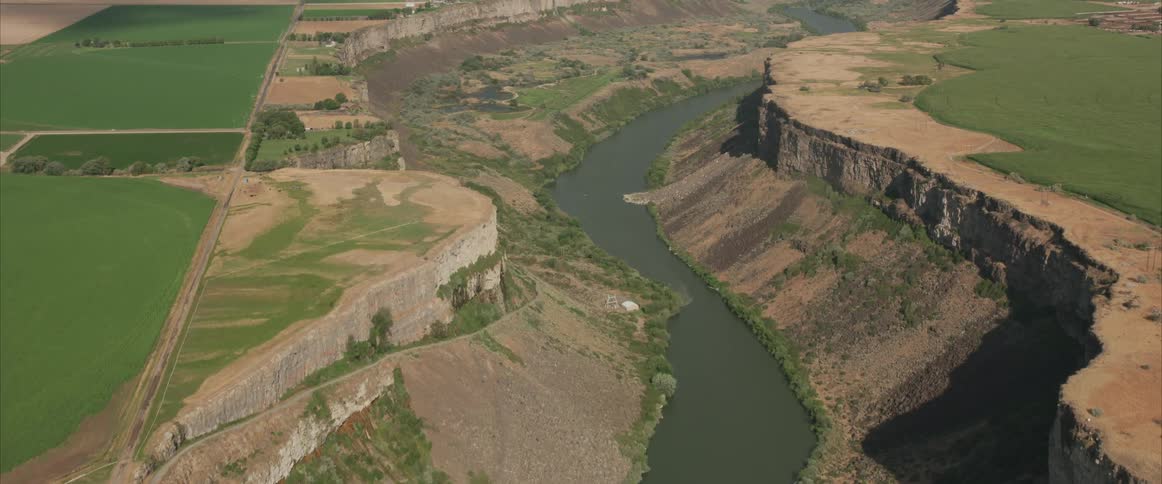 An aerial view of a river next to mountains is displayed