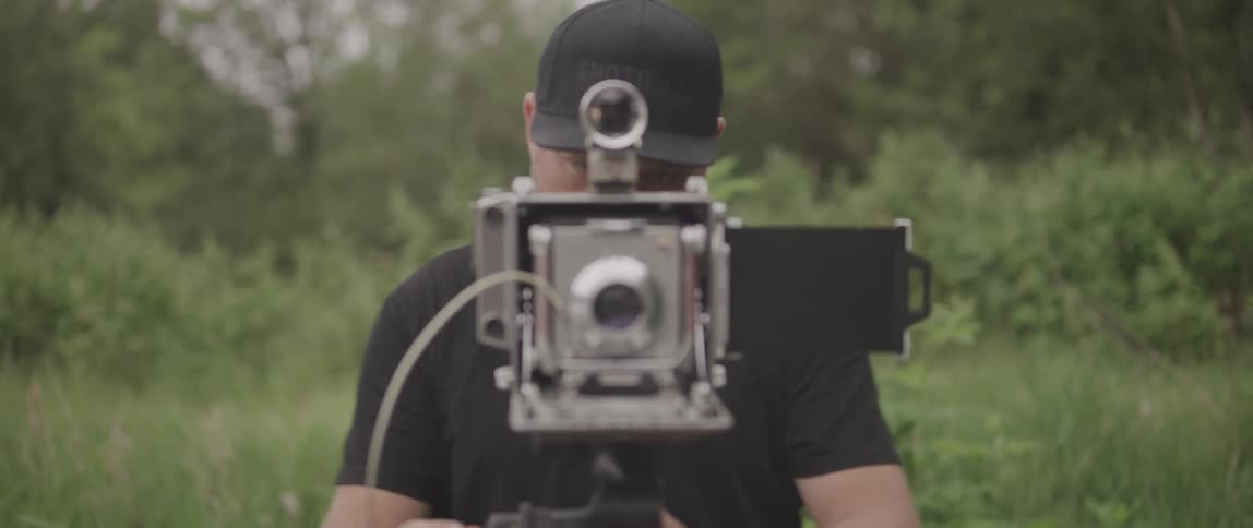 A man makes adjustments to an old fashioned camera before preparing to take a photo with it