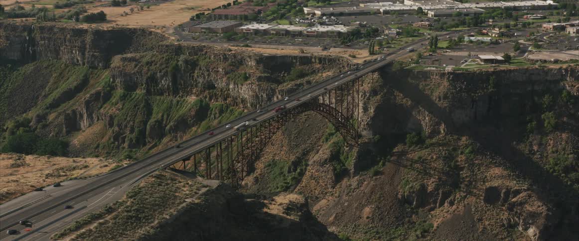 A bridge with cars driving over a canyon and a river