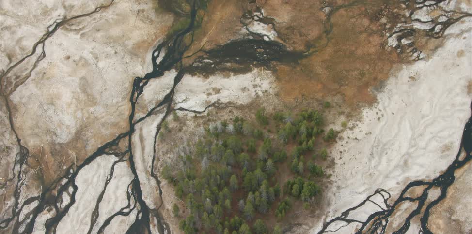 Dark rivers form tendrils across plains near geothermal area and forests