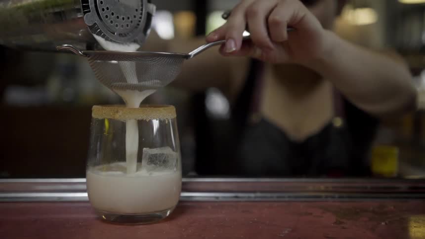 Cocktail is poured through a strainer