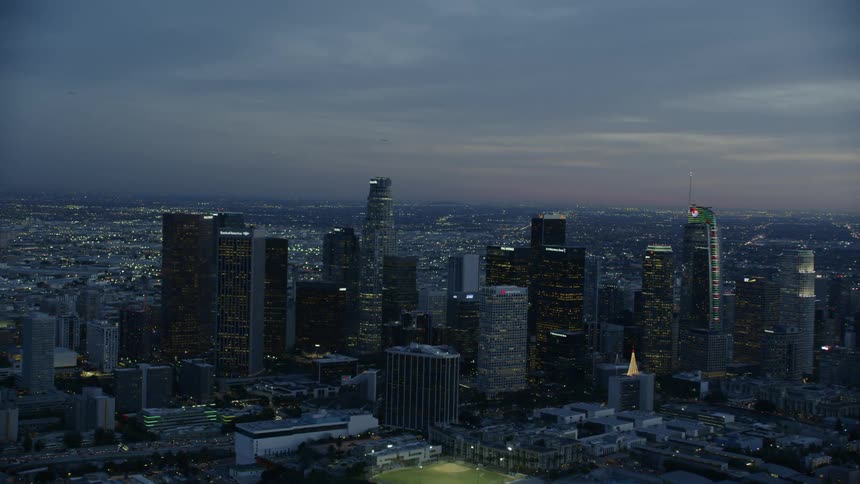 An aerial view of a downtown city is displayed at night