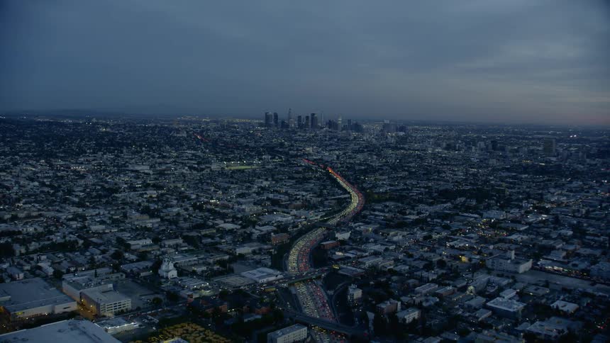 Aerial view of a winding highway with evening traffic leading to a Downtown City